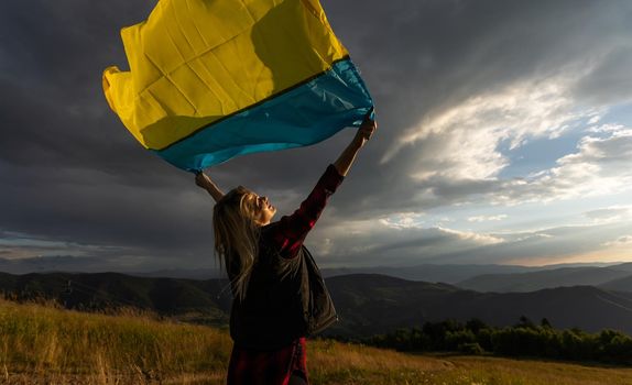 Woman holding a yellow and blue flag of Ukraine in outdoors. Independence Day. Flag Day. Constitution day. Woman in traditional embroidery with flag of Ukraine