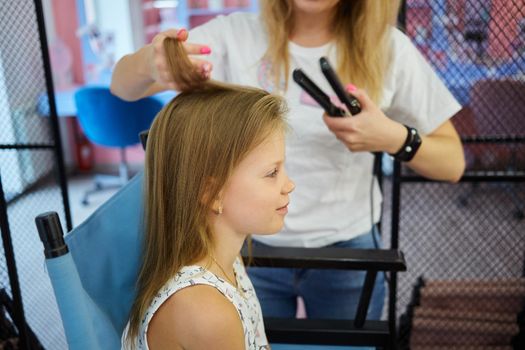 Hairdressing services. Reating hairstyle. Hair styling process. Children hairdressing salon.