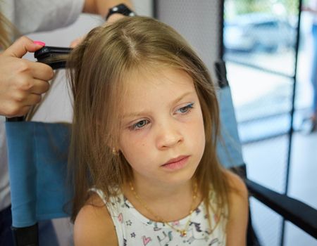 Hairdressing services. Reating hairstyle. Hair styling process. Children hairdressing salon.