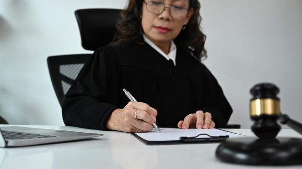 Professional female lawyer signing papers with gavel putting on white table. Lawyer, justice and law ,attorney concept.