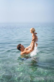 Dad with a little girl in his arms bathes in the sea. High quality photo