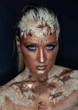 Portrait of female model with creative prehistoric makeup with cave painting