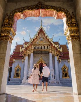 Wat Benchamabophit temple in Bangkok Thailand, The Marble temple in Bangkok. Asian woman with hat and European men visiting a temple, a couple on a city trip in Bangkok