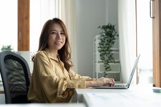 Portrait smiling young asian female accountant working on laptop computer in office.