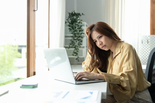 Tired asian business woman with headache at office, feeling sick at work, copy space.