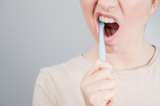 Close-up portrait of caucasian woman brushing her teeth. The girl performs the morning oral hygiene procedure.