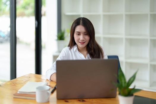 Portrait of a beautiful Asian businesswoman at work office desk with laptop computer in office.