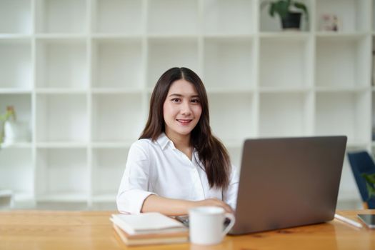 Portrait of a beautiful Asian businesswoman at work office desk with laptop computer in office.