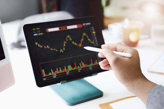 Investment professionals point their pen at their computer monitor to analyze the stock market for profit