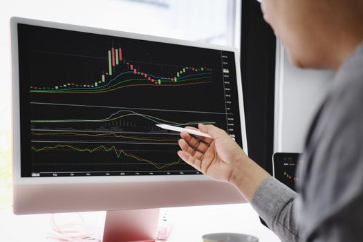 Investment professionals point their pen at their computer monitor to analyze the stock market for profit