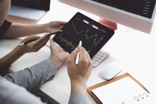 An investment expert points a pen at a computer monitor to analyze the stock market to teach you how to make a profit