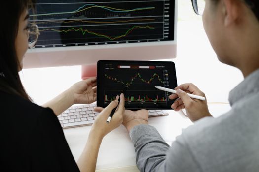 An investment expert points a pen at a tablet monitor to analyze the stock market to teach you how to make a profit