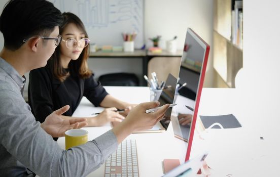 An investment expert points a pen at a computer monitor to analyze the stock market to teach you how to make a profit