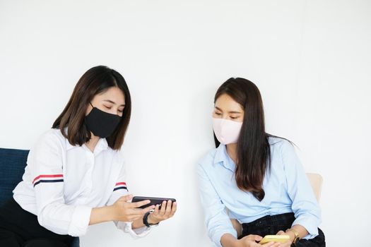 social distancing concept, Two women wearing masks and distancing while sitting on mobile phones following coronavirus social trend