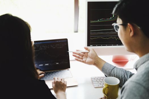 An investment expert points a pen at a computer monitor to analyze the stock market to teach you how to make a profit