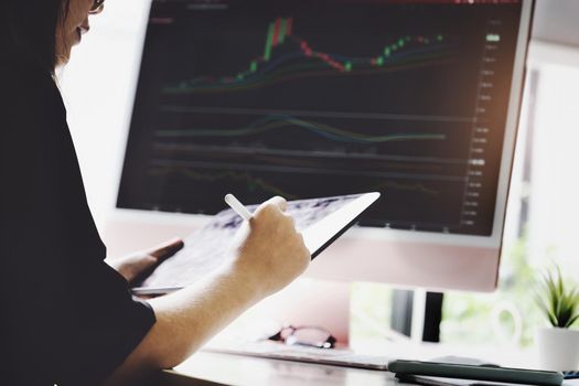 New normal, self-employed women hand holding pen are using tablet and computer laptop to trade stocks for profit, buying and selling