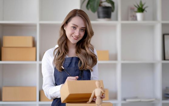 Startup SME small business entrepreneur SME or freelance Asian woman using a laptop with box, Young success Asian woman with her hand lift up, online marketing packaging box and delivery, SME concept..