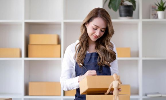 Successful Asian women entrepreneur with parcel boxes in her own job shopping online business at home office. start up small business, sme concept..