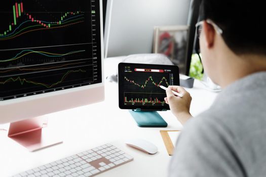 Investment professionals point their pen at their computer monitor to analyze the stock market for profit