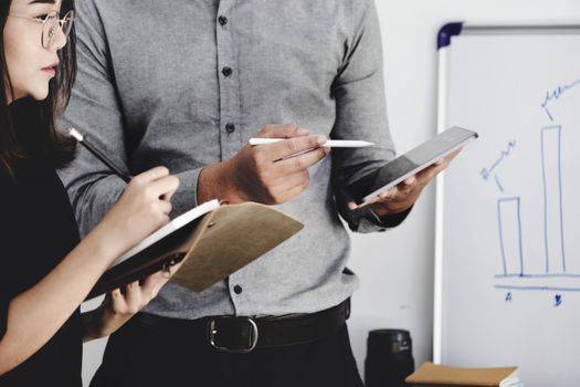 An investment expert points a pen at a tablet monitor to analyze the stock market to teach you how to make a profit