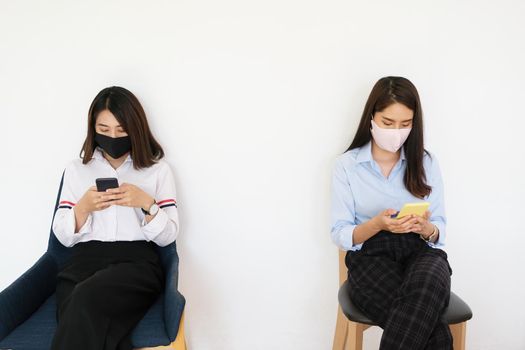 social distancing concept, Two women wearing masks and distancing while sitting on mobile phones following coronavirus social trend