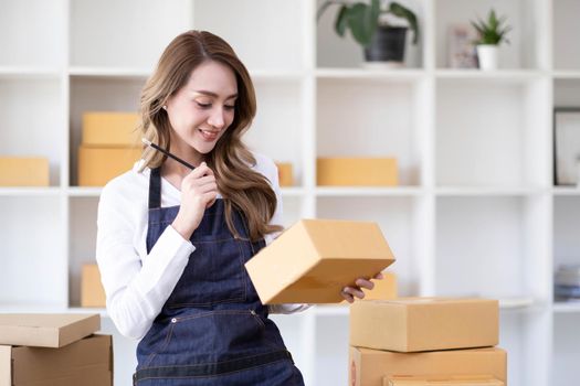 Portrait of Asian young woman SME working with a box at home the workplace.start-up small business owner, small business entrepreneur SME or freelance business online and delivery concept..