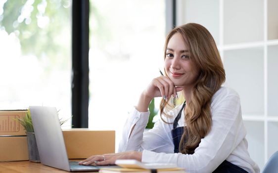 Portrait of Asian young woman SME working with a box at home the workplace.start-up small business owner, small business entrepreneur SME or freelance business online and delivery concept..