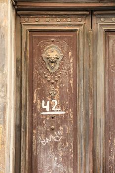 Cartagena, Murcia, Spain- July 17, 2022:Old wooden door and vintage lion face shaped knocker in Spain