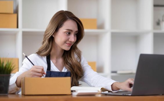 Portrait of Asian young woman SME working with a box at home the workplace.start-up small business owner, small business entrepreneur SME or freelance business online and delivery concept..