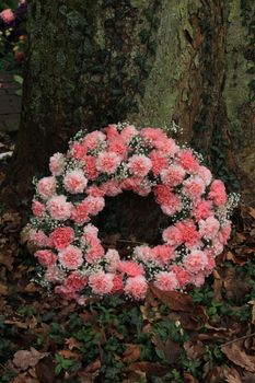 Pink sympathy or funeral flowers near a tree at a cemetery