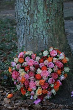 Heart Shaped sympathy or funeral flowers near a tree at a cemetery