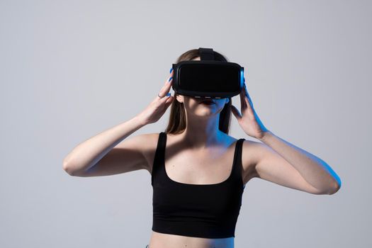 Pretty beautiful cute excited woman in VR headset looking up and trying to touch objects in virtual reality while playing a game in virtual reality