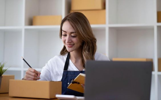 Portrait of Asian young woman SME working with a box at home the workplace.start-up small business owner, small business entrepreneur SME or freelance business online and delivery concept..