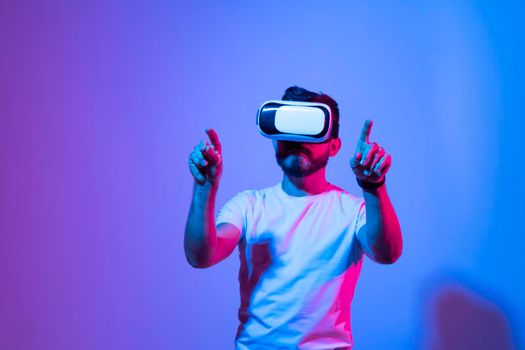 Picture of young man wearing virtual reality headset and playing a videogame online. Future technology