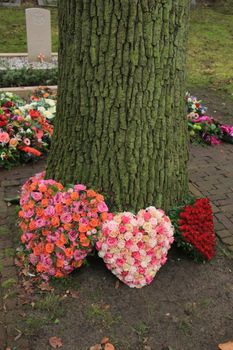 Heart shaped sympathy or funeral flowers near a tree