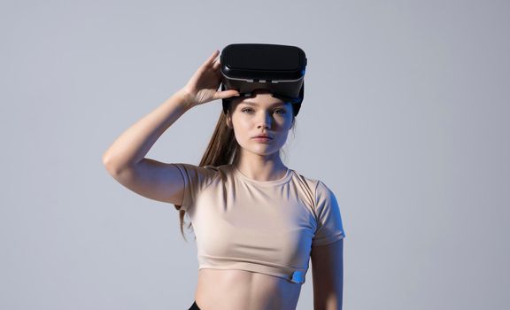 Portrait of young woman wearing a virtual reality headset goggles and ready to play a game with a friends. Future technology concept