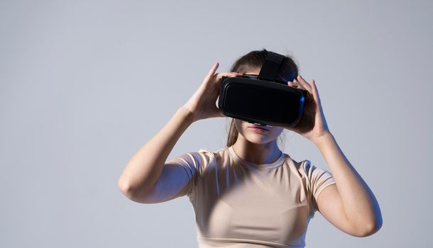 Brunette woman gamer with a virtual reality glasses ready to play a game or explore the environment in a metaverse world. Modern technologies