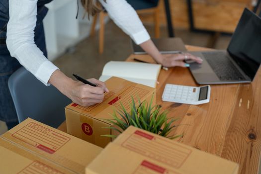 Start up small business entrepreneur SME writing address on the box.Business owner at home office, online marketing packaging and delivery, for SME concept