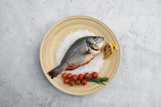 Top view of plate with fresh grilled dorado fish with lemon and tomato
