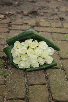 White sympathy roses in a small bouquet on the pavement