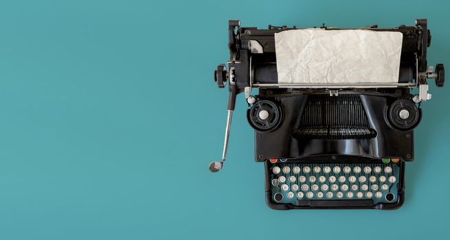 A black vintage typewriter on blue background.