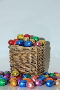 Foil wrapped chocolate easter eggs in a wicker basket