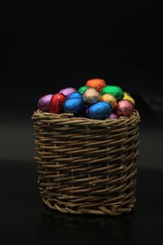 Foil wrapped chocolate easter eggs in a wicker basket