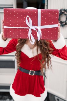 Beauty girl in santa costume with gift box at winter campsite getting ready for the new year. New year celebration concept