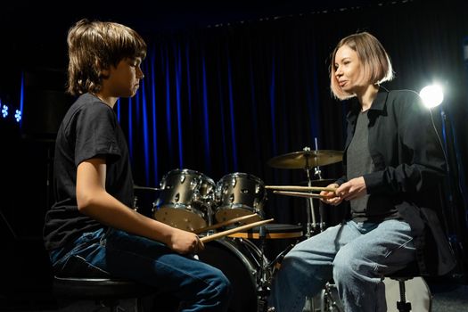 Young woman teaching boy to play drums