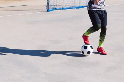 unrecognizable football player stepping on the ball in a concrete football court, concept of healthy lifestyle and urban sport in the city, copy space for text
