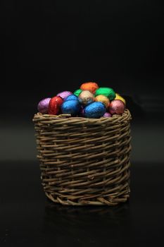 Foil wrapped chocolate easter eggs in a wicker basket