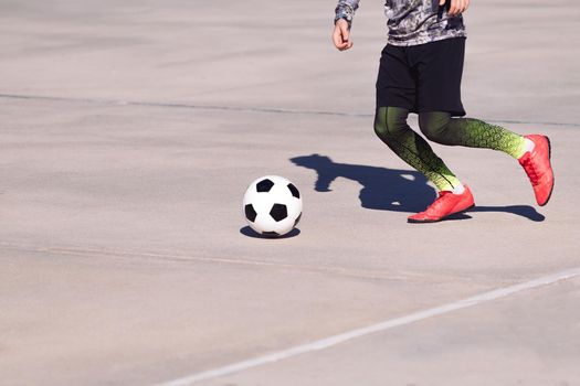 legs of an unrecognizable sportsman running with the ball in a concrete football court, concept of healthy lifestyle and urban sport in the city, copy space for text