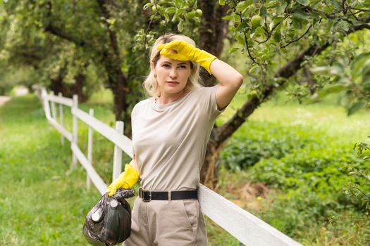 woman picking up garbage and putting it in plastic black bag