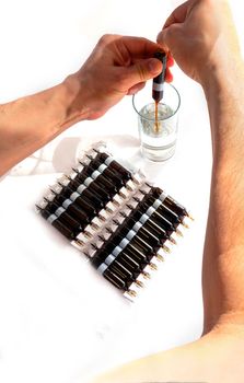 pour solution from an ampoule into a glass, dilute with water. horizontal perspective view of many brown ampoules set in pharmaceutical packaging white container